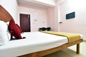 una camera da letto con un letto con lenzuola bianche e cuscini rossi di ROYAL GREEN AIRPORT TRANSIT ACCOMMODATION a Chennai