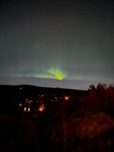 una aurora en el cielo sobre una ciudad por la noche en Cabin with sea, lake and hill view, en Søndeled