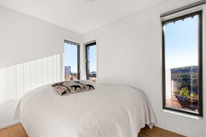 a white bedroom with a bed and windows at sea, lake and hill view - TheHumanBirdHouseRetreat in Søndeled +19 photos