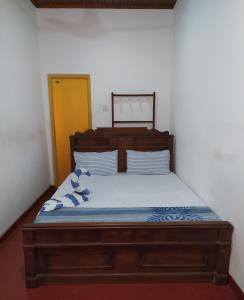 een slaapkamer met een houten bed met blauwe en witte kussens bij River Side Holiday Inn in Weligama