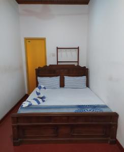 1 dormitorio con cama de madera y almohadas azules y blancas en River Side Holiday Inn, en Weligama