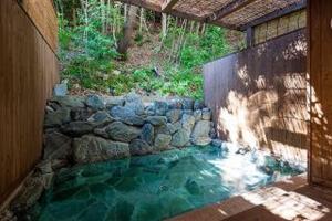 a pool of water with a stone wall at Merveille Arima in Kobe