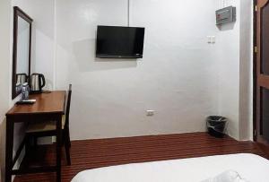 a bedroom with a desk and a tv on the wall at RedDoorz at Diamond Spring Hotel Angeles City in Angeles