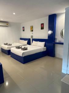 2 Betten in einem blau-weißen Zimmer in der Unterkunft The Cosy Koh Phangan and Restaurant in Thongsala