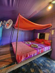 a bed with an orange canopy in a purple room at Sweet Nature Bungalow in Koh Rong Island