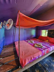 ein Bett mit orangefarbenem Baldachin in einem lila Zimmer in der Unterkunft Sweet Jungle Glamping in Koh Rong