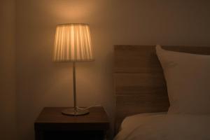 una lámpara sentada en una mesa junto a una cama en セザンヌ, en Hakata