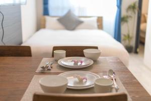 una mesa con platos y tazas y una mesa con una cama en セザンヌ, en Hakata
