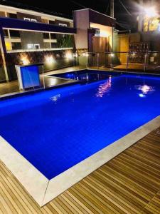 ein großer blauer Pool in einem Gebäude in der Nacht in der Unterkunft Apartamento com piscina/3 min da Praia in Porto Seguro