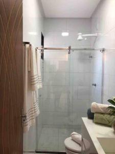 ein Bad mit einer Glasdusche und einem WC in der Unterkunft Apartamento com piscina/3 min da Praia in Porto Seguro