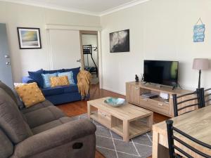 uma sala de estar com um sofá e uma televisão em SummerBreeze - just a 60 second stroll to the beach em Culburra Beach