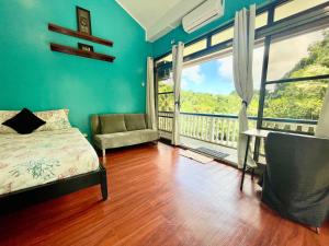 a bedroom with a bed and a chair and a balcony at Ngermid Oasis - Studio W/ Kitchenette & Pool View in Koror