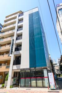 a tall building with glass windows on a street at Ueno Woo Hotel in Tokyo