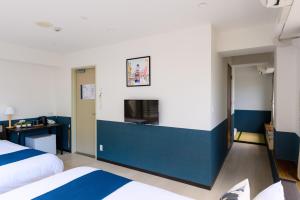 a hotel room with two beds and a blue wall at Ueno Woo Hotel in Tokyo