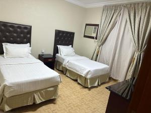 a hotel room with two beds and a window at Al Farhan Hotel Suites Al siteen in Al Jubail