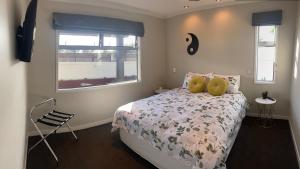 a bedroom with a bed and a chair and a window at Saint Aubyn Retreat in New Plymouth