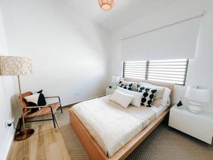 a bedroom with a bed with a lamp and a chair at Stylish Comfy Boho Style Home W/ Parking@ San Juan in San Juan