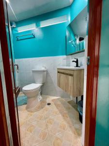 Baño azul con aseo y lavamanos en Ngermid Oasis - Studio W/ Kitchenette & Pool View en Koror