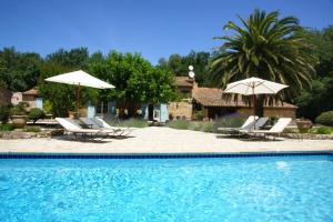 einen Pool mit Stühlen und Sonnenschirmen neben einem Haus in der Unterkunft La Pierrerie in Grimaud