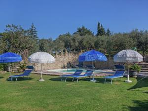 eine Gruppe blauer Stühle und Sonnenschirme neben einem Pool in der Unterkunft Apartment in quiet and green environment with swimming pool in Modigliana