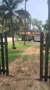 a house with palm trees in front of a field at Casa Ganesha beach residence in Irimbranallūr +3 photos
