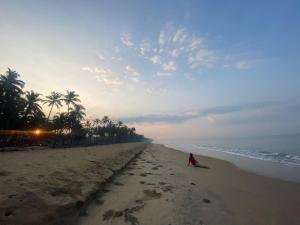 a person sitting on the beach near the ocean at Casa Ganesha beach residence in Irimbranallūr