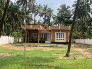 a house with palm trees in front of it at Casa Ganesha beach residence in Irimbranallūr