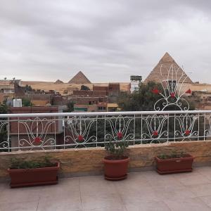een uitzicht op de piramides vanaf een balkon met planten bij Gohar Guest House in Caïro