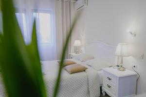 a white bedroom with a bed and a table with a lamp at Hotel Secret Garden in Baia-Sprie