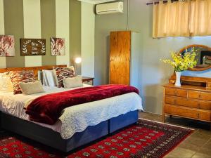 Un dormitorio con una cama y un tocador con un jarrón de flores en The Green Tree Cottages en Alexandria