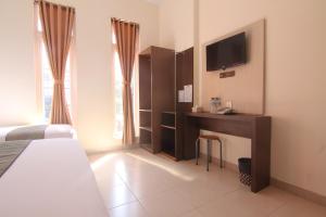 Habitación de hotel con cama y escritorio con TV. en Hotel Pules, en Yogyakarta