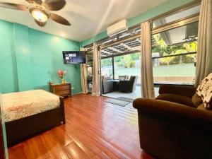 a room with a bed and a couch and a television at Ngermid Oasis- 2 BD Master Suite in Koror