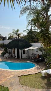 a resort with a swimming pool with an umbrella at Casa Blanca Boutique Hotel Pension in Windhoek