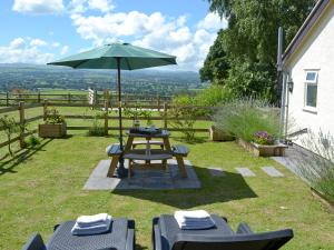 a table and chairs with an umbrella in the grass at Beehive Cottage in Bodfari