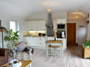 a kitchen and living room with white cabinets and a table at Beehive Cottage in Bodfari