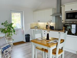a kitchen and dining room with a table and chairs at Beehive Cottage in Bodfari