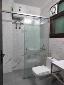 a bathroom with a glass shower with a toilet at Elite 32 Avenue - Near Google Building in Gurgaon