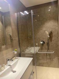 a bathroom with a sink and a glass shower at Lovely studio apartment inside Jebel Sifah resort in As Sīfah