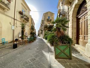 an alley with buildings and palm trees on a street at Elegante appartamento in palazzo storico Ortigia in Siracusa