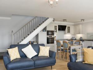 sala de estar con sofá azul y cocina en The Granary Cottage, en Wall Houses