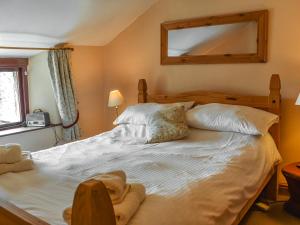 a bedroom with a large white bed with a mirror at Church House Cottage in Ulpha
