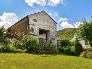 an old building with a bench in a yard at Church House Cottage in Ulpha