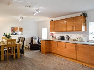 a kitchen with wooden cabinets and a dining room at Muirston Farmhouse in Ochiltree