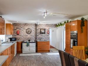 a kitchen with wooden cabinets and a brick wall at Muirston Farmhouse in Ochiltree