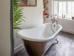 a bath tub in a bathroom with a plant at Thorn Cottage in Winsford