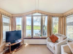 un soggiorno con TV e ampia finestra di Hafod Caravan - Uk45717 a Brynteg