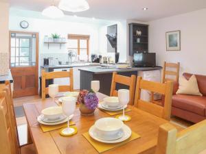 a kitchen and living room with a wooden table and chairs at Hafod in Lower Boscaswell