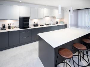 a kitchen with a large white counter and stools at Caledonia View in Aviemore