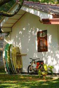 una motocicleta estacionada frente a una casa con tablas de surf en Salty Garden, en Matara
