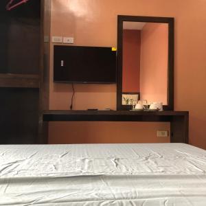 a bedroom with a white bed and a mirror at Alona Princess Suites in Panglao